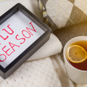Flu season. Background warm woolen clothes, cup of hot lemon tea.
