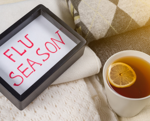 Flu season. Background warm woolen clothes, cup of hot lemon tea.